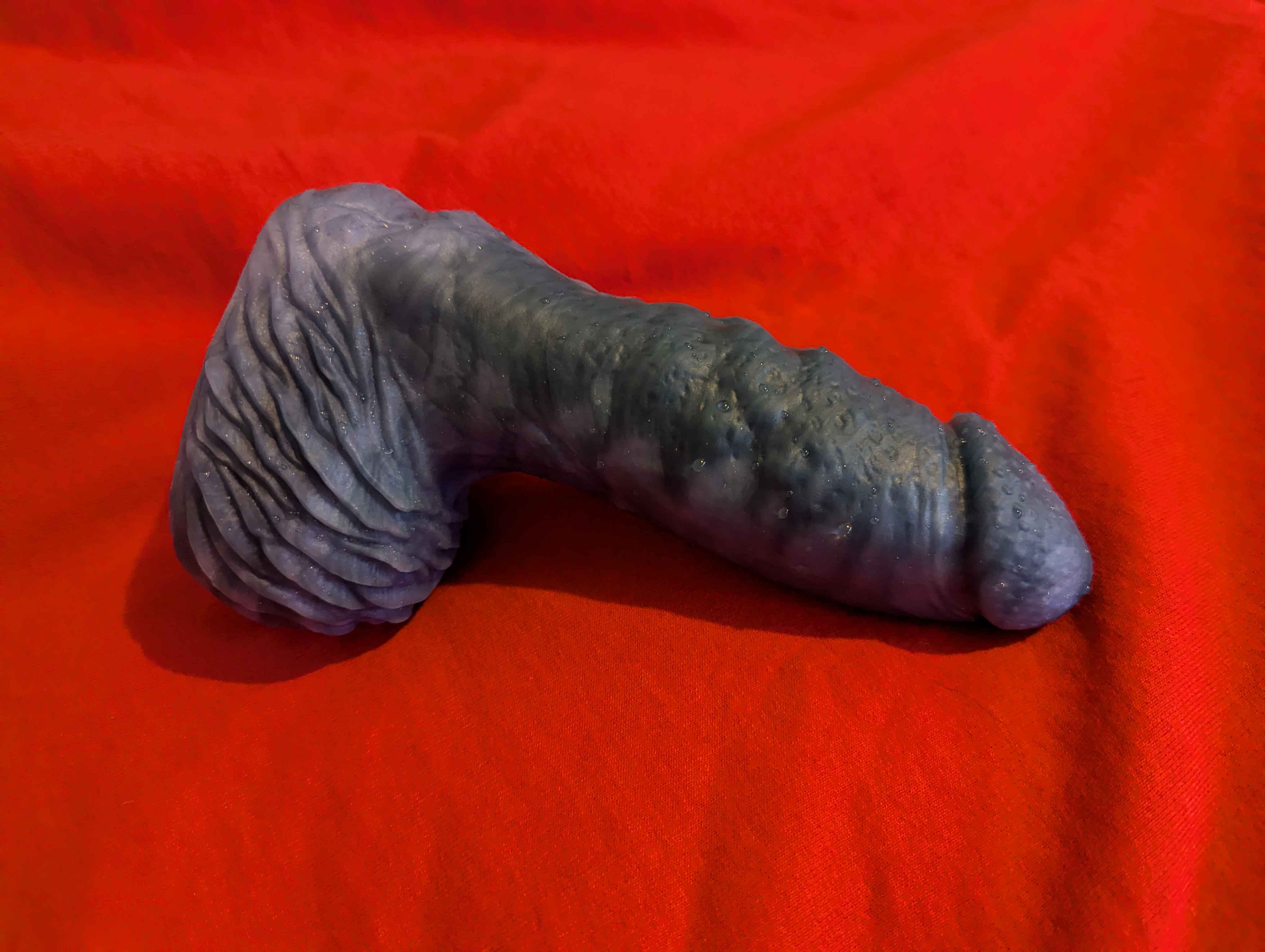 a photo of a marbled blue humanoid dildo on a red hoodie